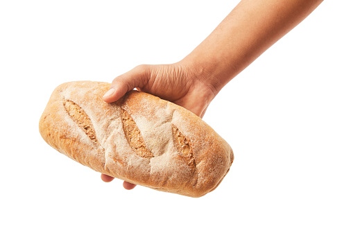 Hand holds a long loaf of bread on white.