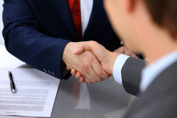 istock Two business man shaking hands to each other above signed contract 693812824