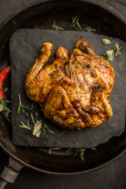 istock Whole raw corn chicken on dark pan. Restaurant. Top view 693812898