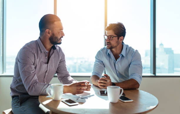 istock Business partners discussing business plans sitting at table in office. 693830174