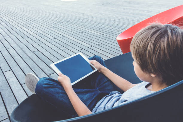 istock Child with tablet computer sitting outdoors. 693847658