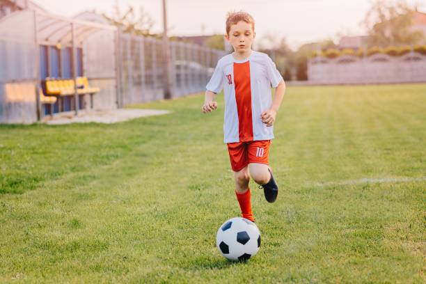 istock 8 years old boy child playing football 693853110