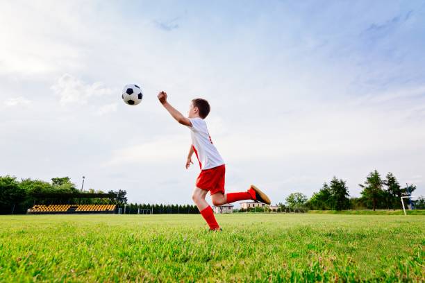 istock 8 years old boy child playing football 693853200
