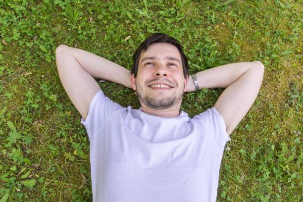 istock Young happy man is relaxing and lying on green grass. 693854438