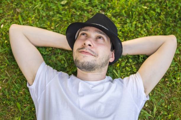 istock Young happy man is lying and relaxing in grass in park and thinking or dreaming. 693856924