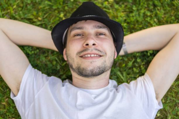 istock Young happy man is lying and relaxing in grass in park. 693857774