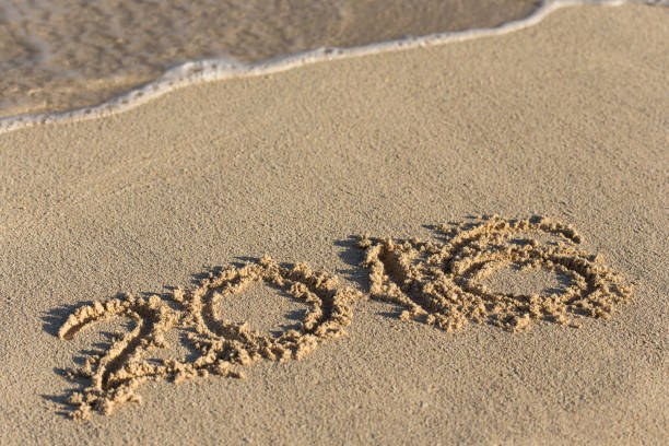 istock Inscription 2016 on sandy beach with wave's foam 693880620