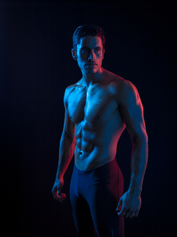Ripped Hispanic Man flexing In Surreal Colored Lighting, red, green, and blue