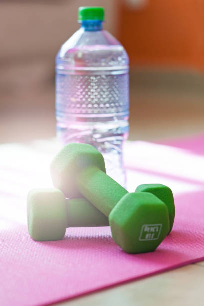 istock Two dumbbells with mineral water on yoga mat 693884630