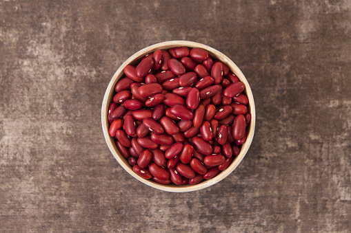 Vegan concept with red beans on brown rustic background.