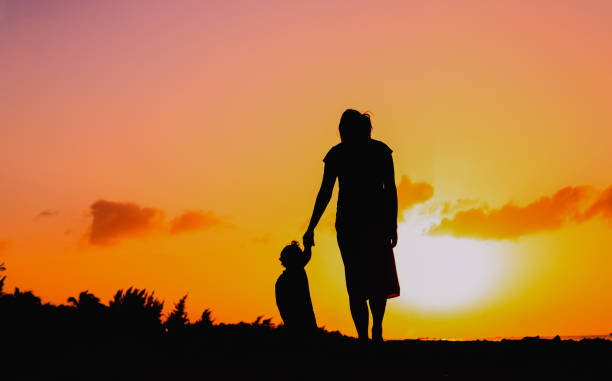 istock mother and daughter walking at sunset 693893950
