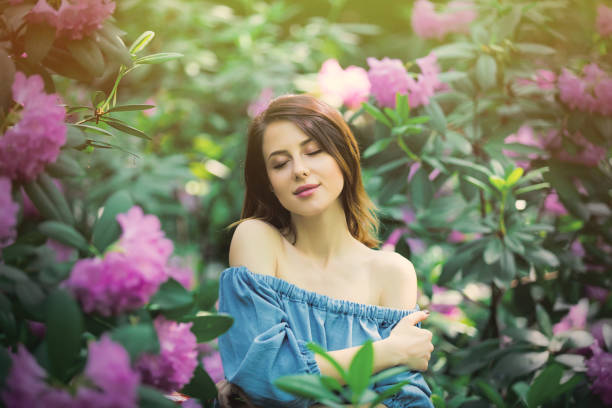 Beautiful young red-haired woman enjoying sunny day in park during blossom flowers season on a nice spring day