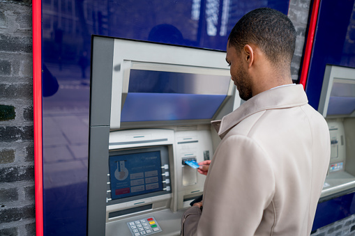 Portrait of a business man withdrawing money from an ATM - financial concepts. Interface on screen was designed from scratch by us.