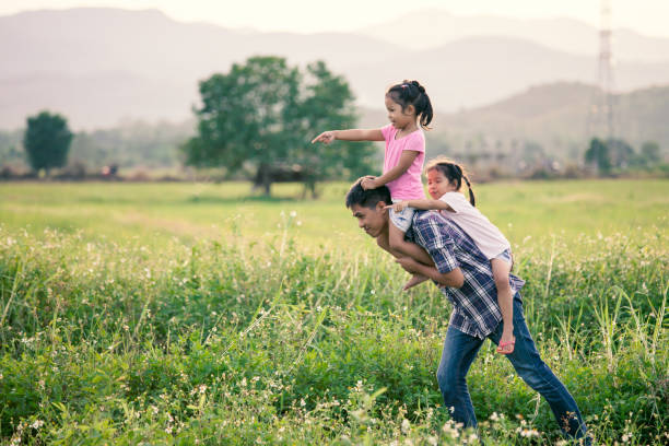 Father and daughter having fun and playing together in the cornfield and child riding on father's back and shoulder in vintage color tone