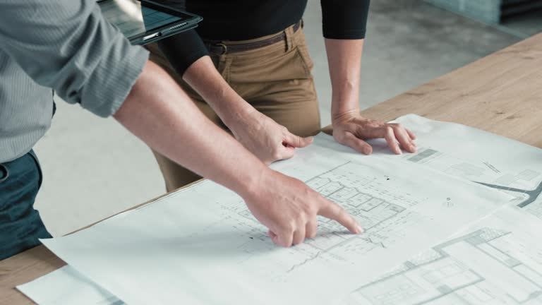 Female architect and male engineer comparing plans on the table with those on the digital tablet at the construction site