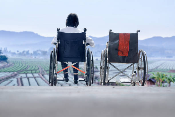 istock Elderly woman with empty wheelchair standing together 693922662