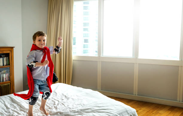 istock Playful superhero little boy jumping on the bed 693928906
