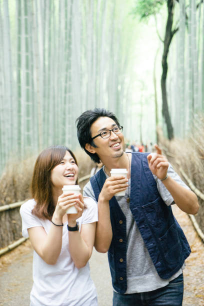 istock Cheerful Japanese couple walking through bamboo forest 693940398