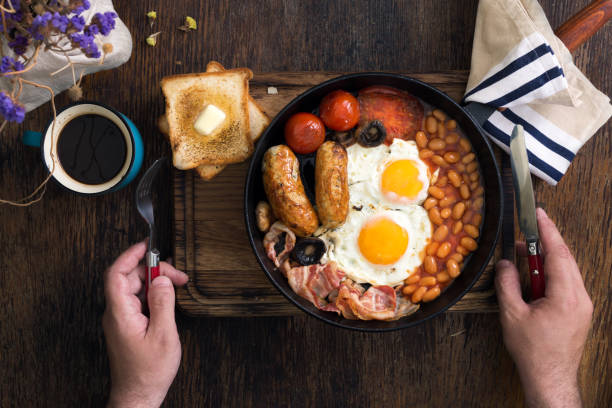 istock Man eats English breakfast on a dark wooden table 693952892
