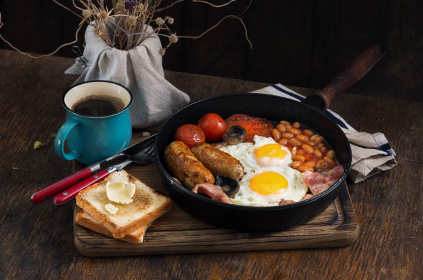 istock English breakfast with sausages, bacon, fried eggs, beans, toast and coffee 693952914