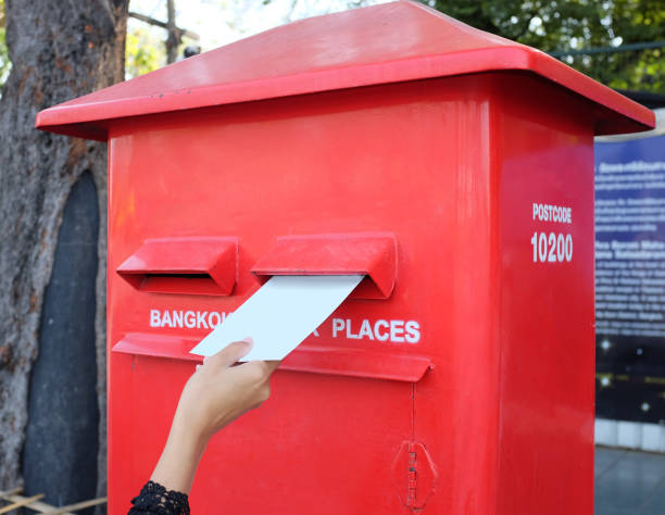 istock Hand sending a letter or postcard in a red Postbox. 693975110