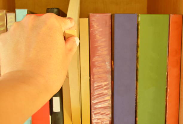 istock hand choose book to read from wooden shelf 693975636