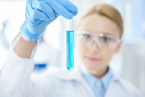 Close-up view of professional scientist holding test tube with reagent in lab
