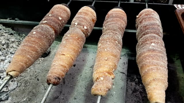 Rotisserie of buns on some metal spits in an open oven in some street in Europe