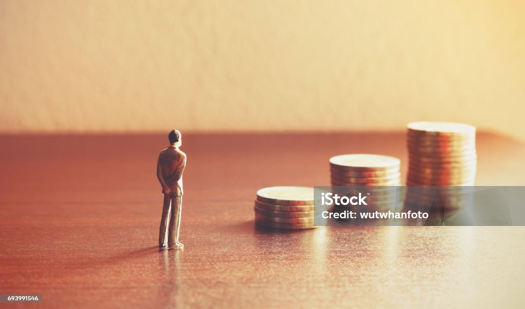 Persone in miniatura che guardano al futuro con stack coin sul concetto di risparmio finanziario e monetario. - Foto stock royalty-free di Valuta