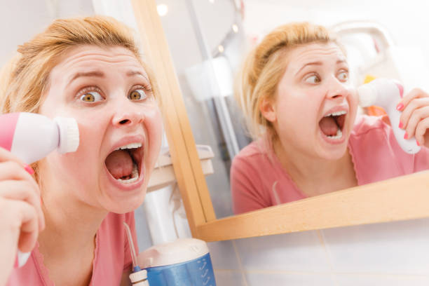 istock Shocked woman using facial cleansing brush 693994194
