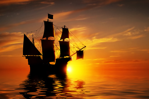 Old ancient pirate ship on peaceful ocean at sunset. Calm waves reflection, sun setting.