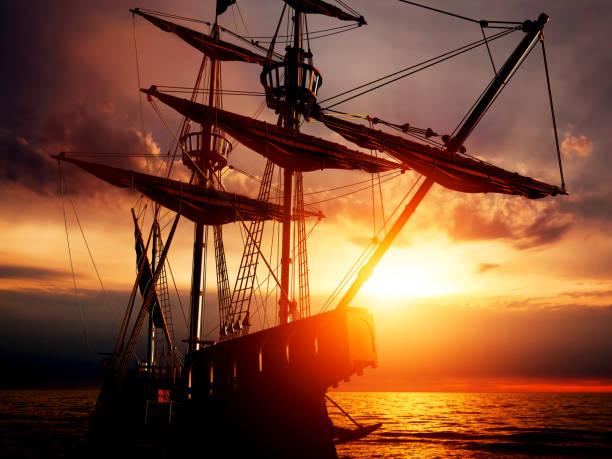 Old ancient pirate ship on peaceful ocean at sunset. Old ancient pirate ship on peaceful ocean at sunset. Calm waves reflection, sun setting. frigate stock pictures, royalty-free photos & images