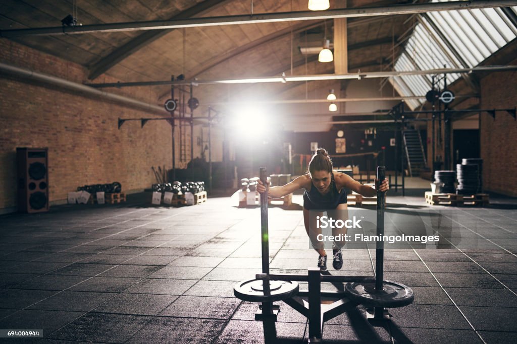 Woman doing hard push-up exercise in gym Sportive woman pushing bogie in gym. Horizontal indoors shot Athlete Stock Photo