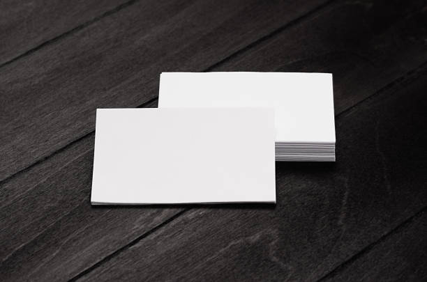 istock Stack blank corporate identity business cards on black stylish wood background with blur, mock up. 694005088