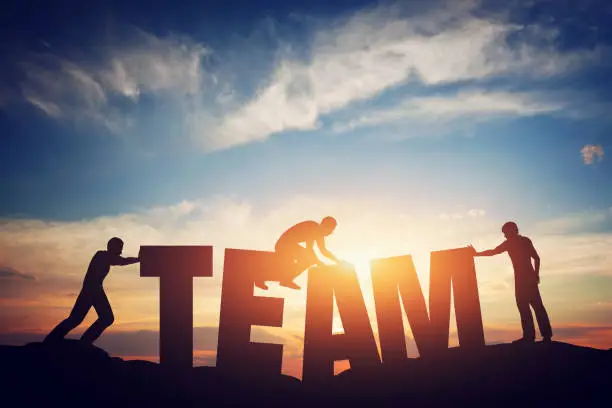 People connect letters to compose the team word. Teamwork concept, idea. Sunset positive light.