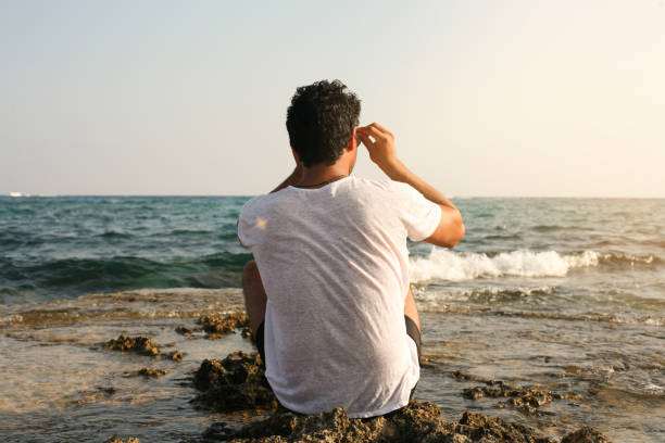 istock Arabian man on the beach. Arabian man sitting on coastline. Space for copy. 694005480