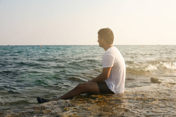 istock Arabian man on the beach. Arabian man sitting on coastline. Space for copy. 694007936