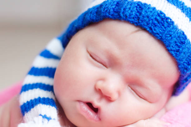 istock Cute newborn baby in blue striped knitted cap sleeping. Infant sleeping 694009330