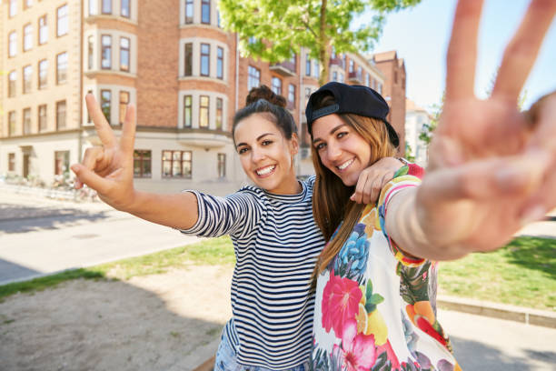 istock Pair of sisters gesturing a V symbol with fingers 694015898