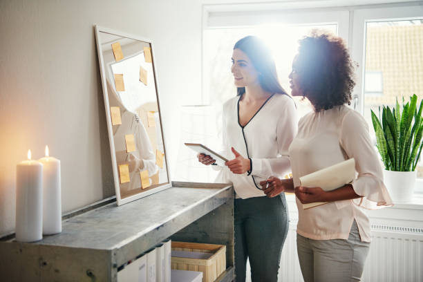 istock Two pretty cheerful multiracial entrepreneurs with tablet 694016260