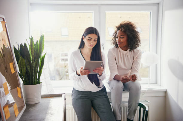 istock Two pretty young multiracial coworkers browsing tablet 694018944