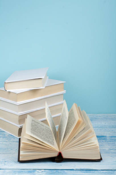 istock Book stacking. Open book, hardback books on wooden table and blue background. Back to school. Copy space for text 694019878