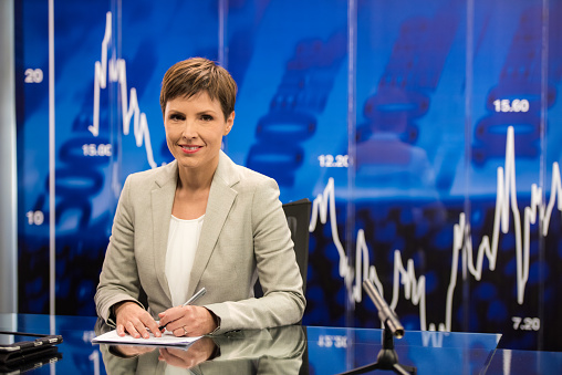 Portrait of newsreader sitting in television studio.