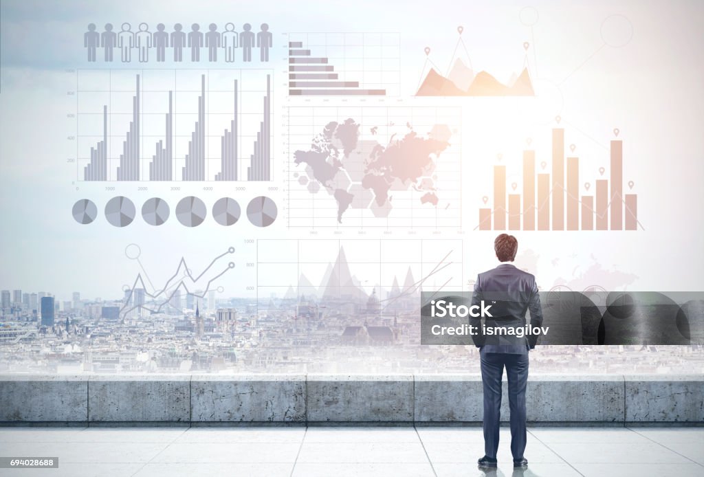 Businessman on roof, graphs and city Rear view of a businessman looking at a gray cityscape in front of him. Gray holograms of graphs in the sky. Elements of this image furnished by NASA. Toned image, double exposure Market Research Stock Photo