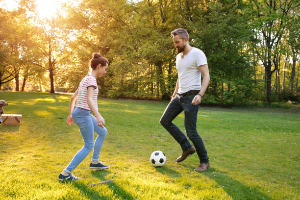 istock Father and daughter playing soccer in park 694040346