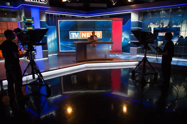 Newsreader filming in press room Cameraman capturing live shooting of news reader in television studio. newscaster photos stock pictures, royalty-free photos & images