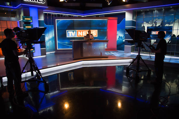 Newsreader filming in press room Cameraman capturing live shooting of news reader in television studio. newscaster stock pictures, royalty-free photos & images