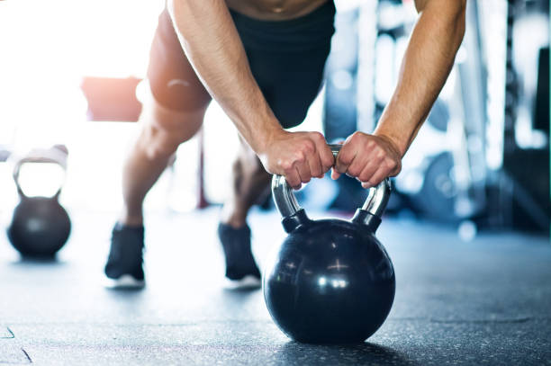 Unrecognizable fit man in gym doing push ups on kettlebells Unrecognizable young fit man doing strength training, doing push ups on kettlebells in modern gym. kettlebell stock pictures, royalty-free photos & images