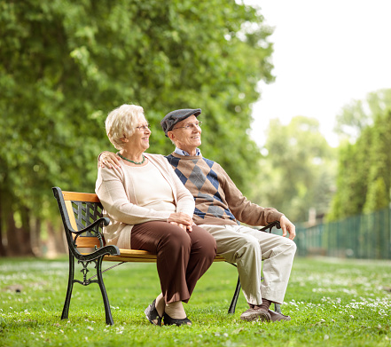 Senior couple sitting on a bench in the park and looking away