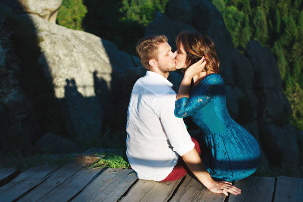 istock Kissing couple sitting on wooden path 694057520